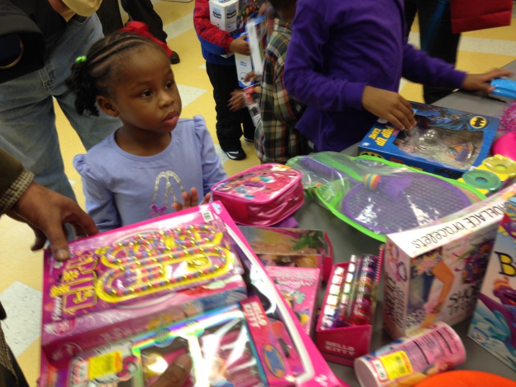 A little girl looks at a table of donated gifts. (WTOP/Megan Cloherty)