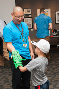 Dr. Albert Chi gives a high-five to a child with a new prosthetic hand, made from a 3-D printer. (Courtesy Jen Own/e-NABLE)
