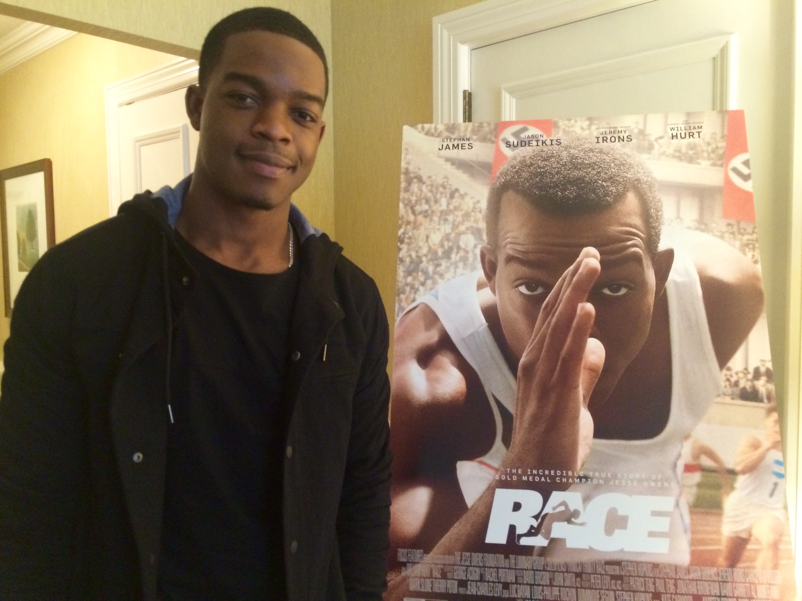 Actor Stephan James poses next to a poster of "Race" during a visit to Dupont Circle in D.C. (WTOP/Jason Fraley)