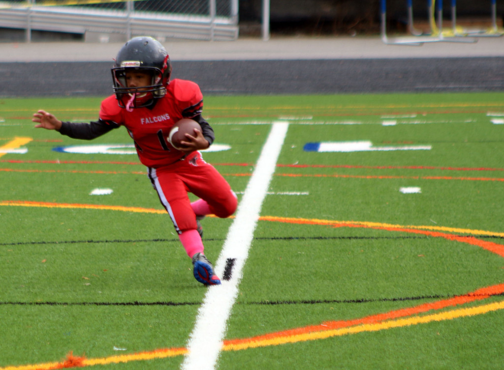A boy who's a football player runs with a football