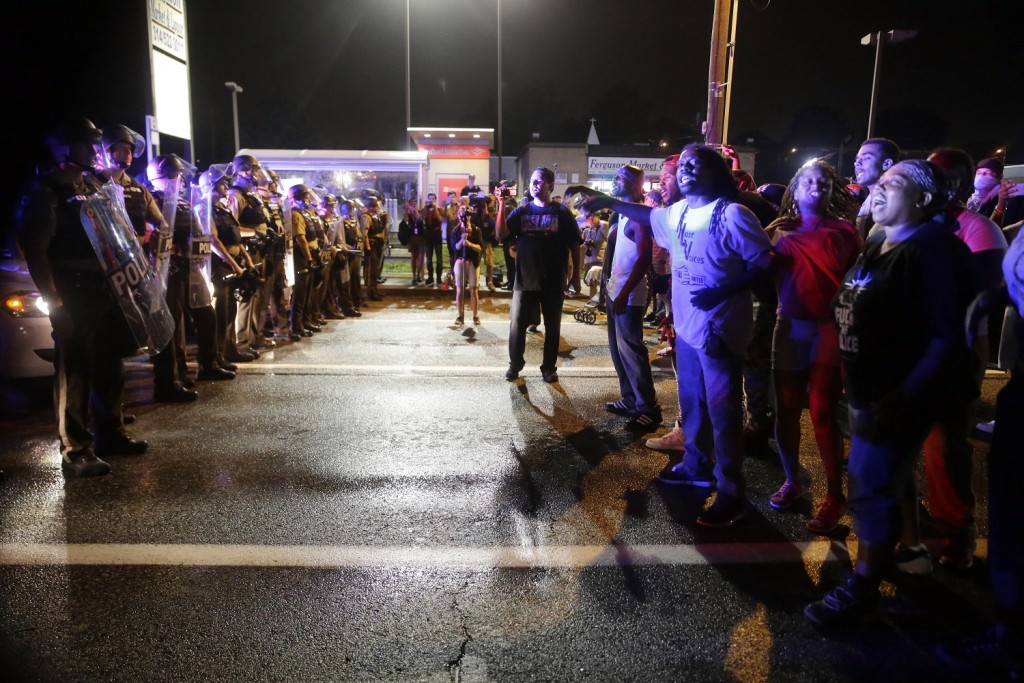 Protesters yell as police form a line across West Florissant Ave., Sunday, Aug. 9, 2015, in Ferguson, Mo., on the one-year anniversary of Michael Brown's death. (AP Photo/Jeff Roberson)