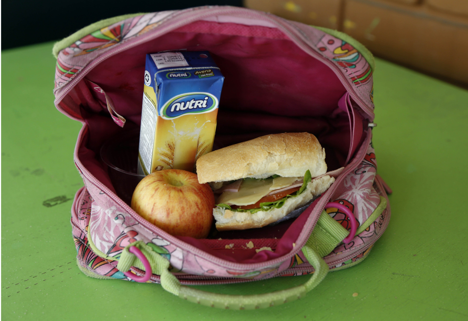 A student's lunch box brought from home sits on display at an elementary school in Quito, Ecuador, Tuesday, May 6, 2014. The lunch consists of a sandwich of ham, cheese, tomato and lettuce, a boxed oatmeal drink, and an apple. (AP Photo/Dolores Ochoa)