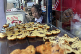 A public elementary school girl buys a pancake for her lunch on the street in Jakarta, Indonesia, Tuesday, May 6, 2014. In Indonesia, not every student can bring a lunch box to school. Public school students buy their lunch at school cafeterias or food stalls on the nearby streets. The price for one pancake is about one U.S. cent. (AP Photo/Achmad Ibrahim)