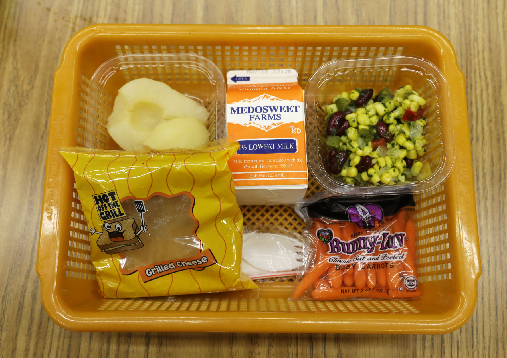 A school lunch featuring a grilled cheese sandwich on whole grain bread is served with a southwestern-style corn salad, fresh carrots and either canned pears or apple sauce Monday, May 5, 2014, at Mirror Lake Elementary School in Federal Way, Wash., south of Seattle. On this day, students could choose between this lunch or a green salad entree option featuring low-sodium chicken, a whole-grain roll, fresh red peppers, and cilantro dressing. (AP Photo/Ted S. Warren)