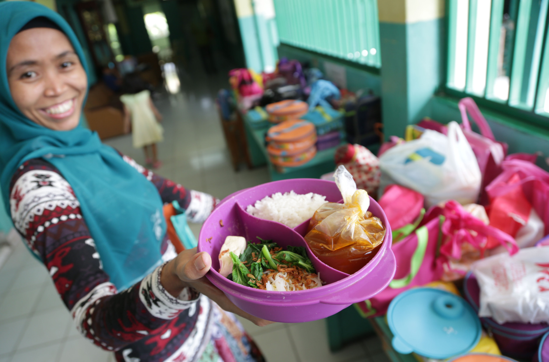 Sri, a house maid, shows a lunch box she prepared for her employer's child, at an elementary school in Jakarta, Indonesia, Tuesday, May 6, 2014. The lunch consists of rice, meatball soup, and tofu and vegetables. Most countries put a premium on feeding school children a healthy meal at lunchtime. The new American standards for school lunches are giving kids in the United States a taste of the good life already experienced by school children around the world. (AP Photo/Achmad Ibrahim)