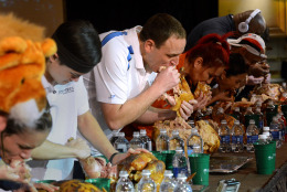 In this Nov. 22, 2014 photo, Joey Chestnut, center, and the other eaters participate in the World Turkey-Eating Championship at Foxwoods Resort and Casino in Mashantucket, Conn. Chestnut won the contest in Connecticut, setting a record by devouring an entire bird. (AP Photo/The Day, Dana Jensen)  MANDATORY CREDIT