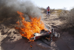 FOR USE AS DESIRED, YEAR END PHOTOS - FILE - Honda rider Paulo Goncalves of Portugal, right, reacts as he sees his motorcycle on fire during the fifth stage of the Dakar Rally between the cities of Chilecito and Tucuman in San Miguel de Tucuman, Argentina, Thursday, Jan. 9, 2014. (AP Photo/Victor R. Caivano, File)