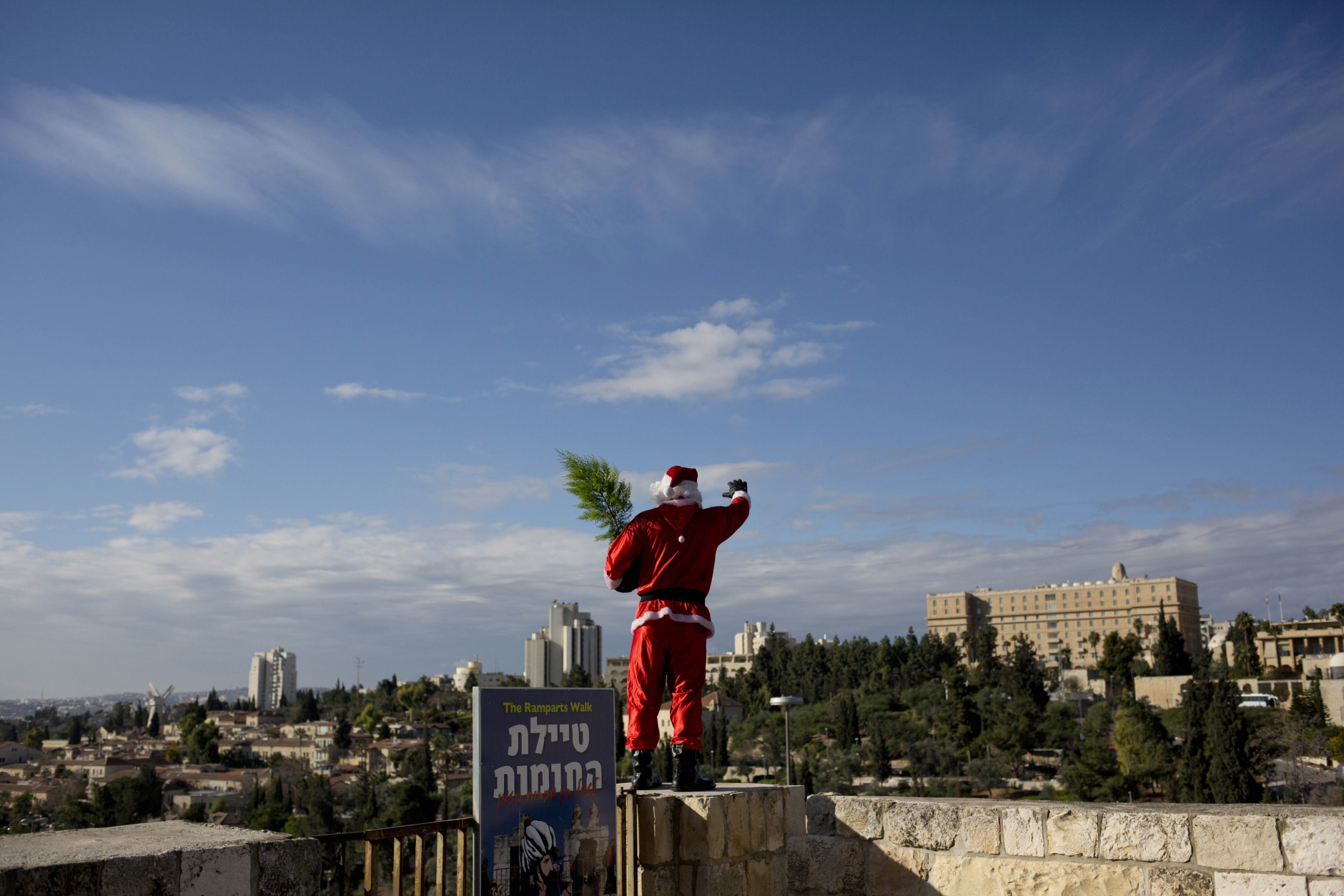 A man dressed as Santa Claus stands on the wall of the Old City in Jerusalem Monday, Dec. 22, 2014. (AP Photo/Dusan Vranic)