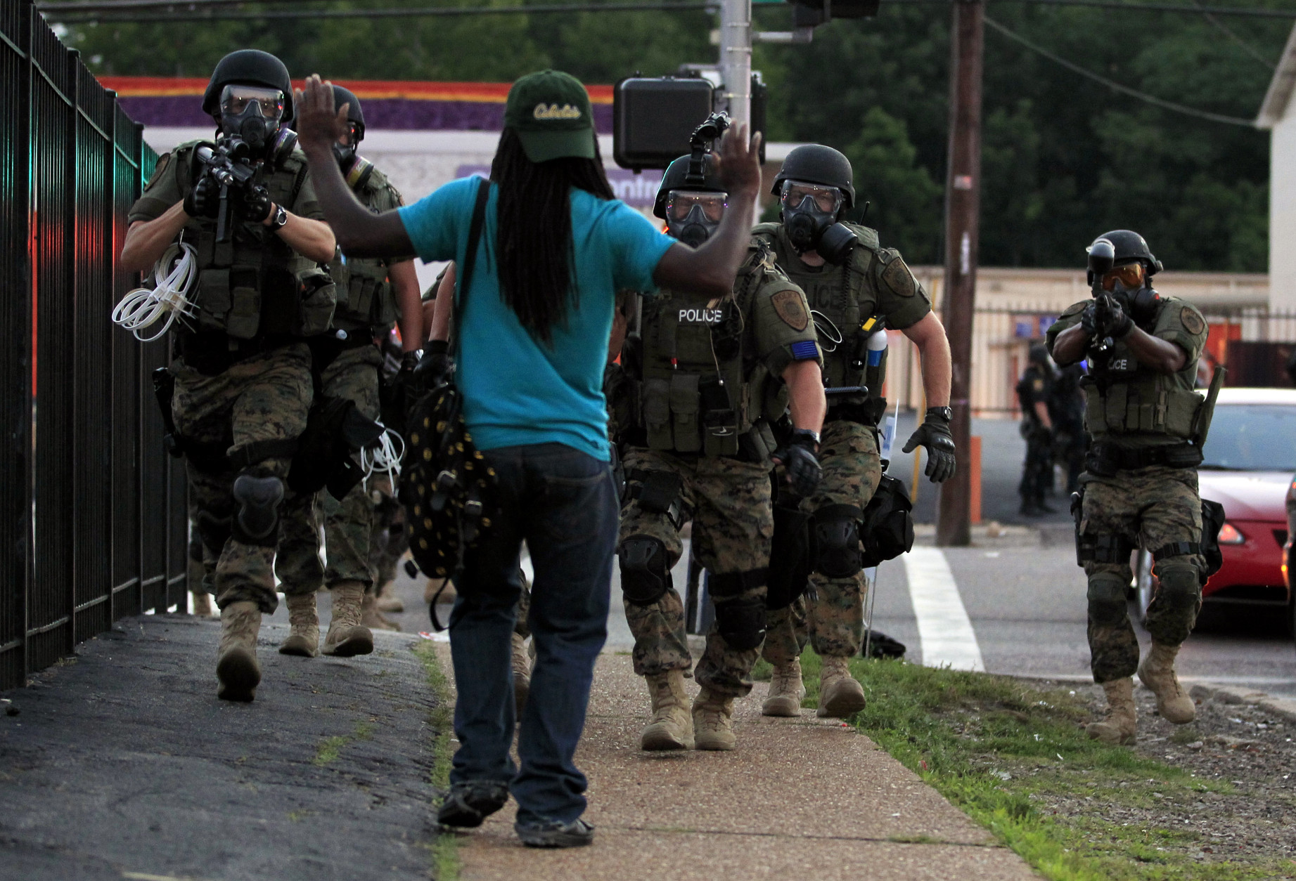 FOR USE AS DESIRED, YEAR END PHOTOS - FILE - Police wearing riot gear walk toward a man with his hands raised Monday, Aug. 11, 2014, in Ferguson, Mo. (AP Photo/Jeff Roberson, File)