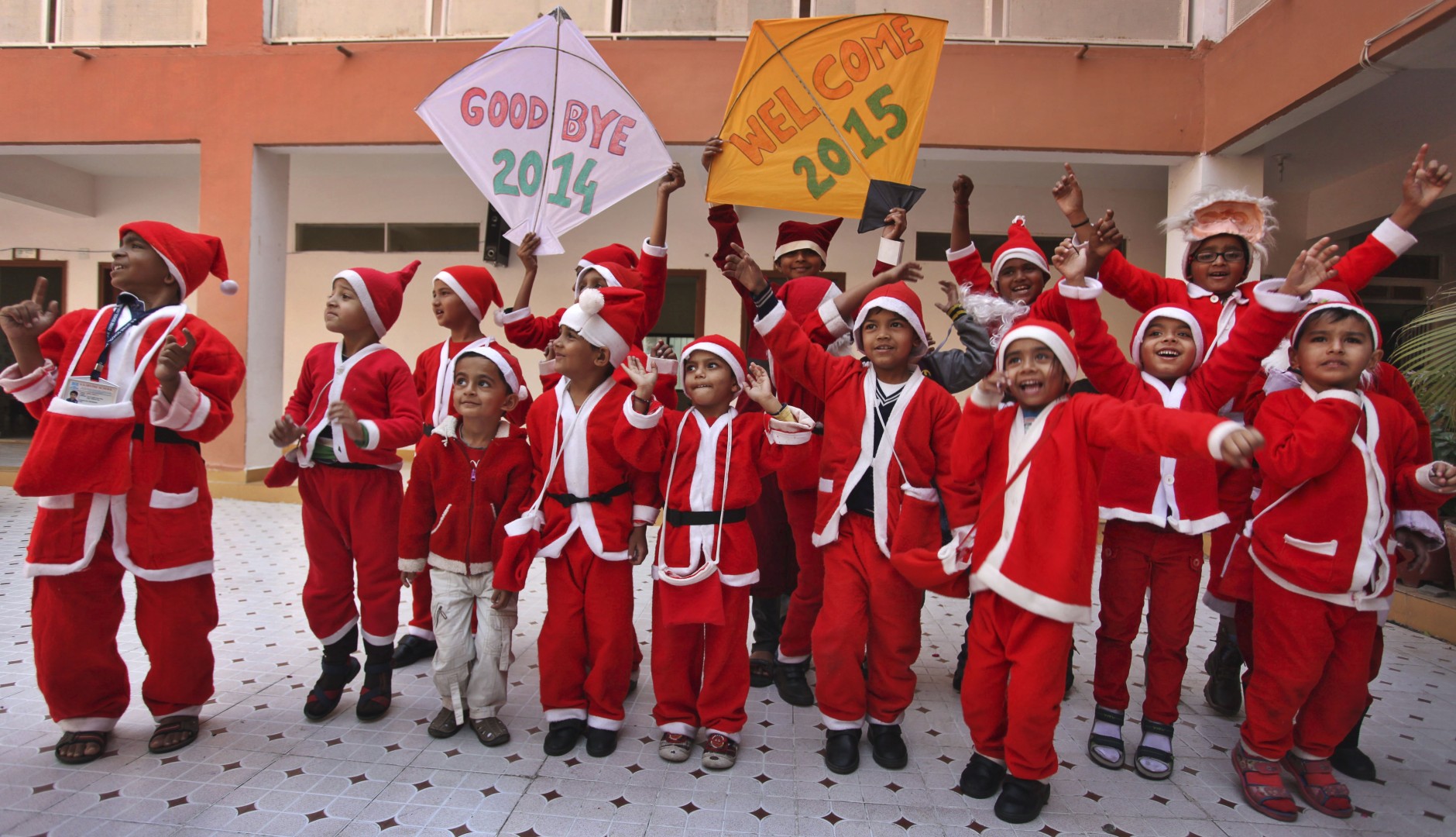 Indian students dressed as Santa Claus hold kites and dance as they participate in a function to welcome the New Year at a school in Ahmadabad, India, Wednesday, Dec. 31, 2014. (AP Photo/Ajit Solanki)
