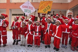 Indian students dressed as Santa Claus hold kites and dance as they participate in a function to welcome the New Year at a school in Ahmadabad, India, Wednesday, Dec. 31, 2014. (AP Photo/Ajit Solanki)