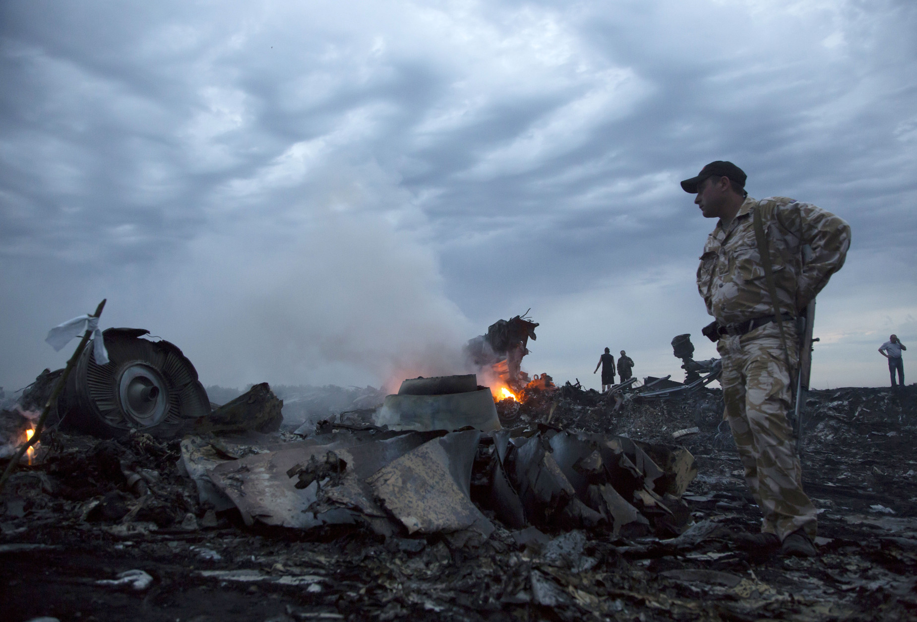 FOR USE AS DESIRED, YEAR END PHOTOS - FILE - People walk amongst the debris, at the crash site of a passenger plane near the village of Grabovo, Ukraine, Thursday, July 17, 2014.  A Ukrainian official said a passenger plane carrying 295 people was shot down as it flew over the country and plumes of black smoke rose up near a rebel-held village in eastern Ukraine. Malaysia Airlines tweeted that it lost contact with one of its flights as it was traveling from Amsterdam to Kuala Lumpur over Ukrainian airspace.  (AP Photo/Dmitry Lovetsky, File)