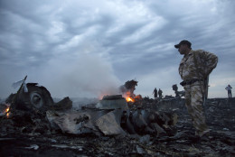 FOR USE AS DESIRED, YEAR END PHOTOS - FILE - People walk amongst the debris, at the crash site of a passenger plane near the village of Grabovo, Ukraine, Thursday, July 17, 2014.  A Ukrainian official said a passenger plane carrying 295 people was shot down as it flew over the country and plumes of black smoke rose up near a rebel-held village in eastern Ukraine. Malaysia Airlines tweeted that it lost contact with one of its flights as it was traveling from Amsterdam to Kuala Lumpur over Ukrainian airspace.  (AP Photo/Dmitry Lovetsky, File)