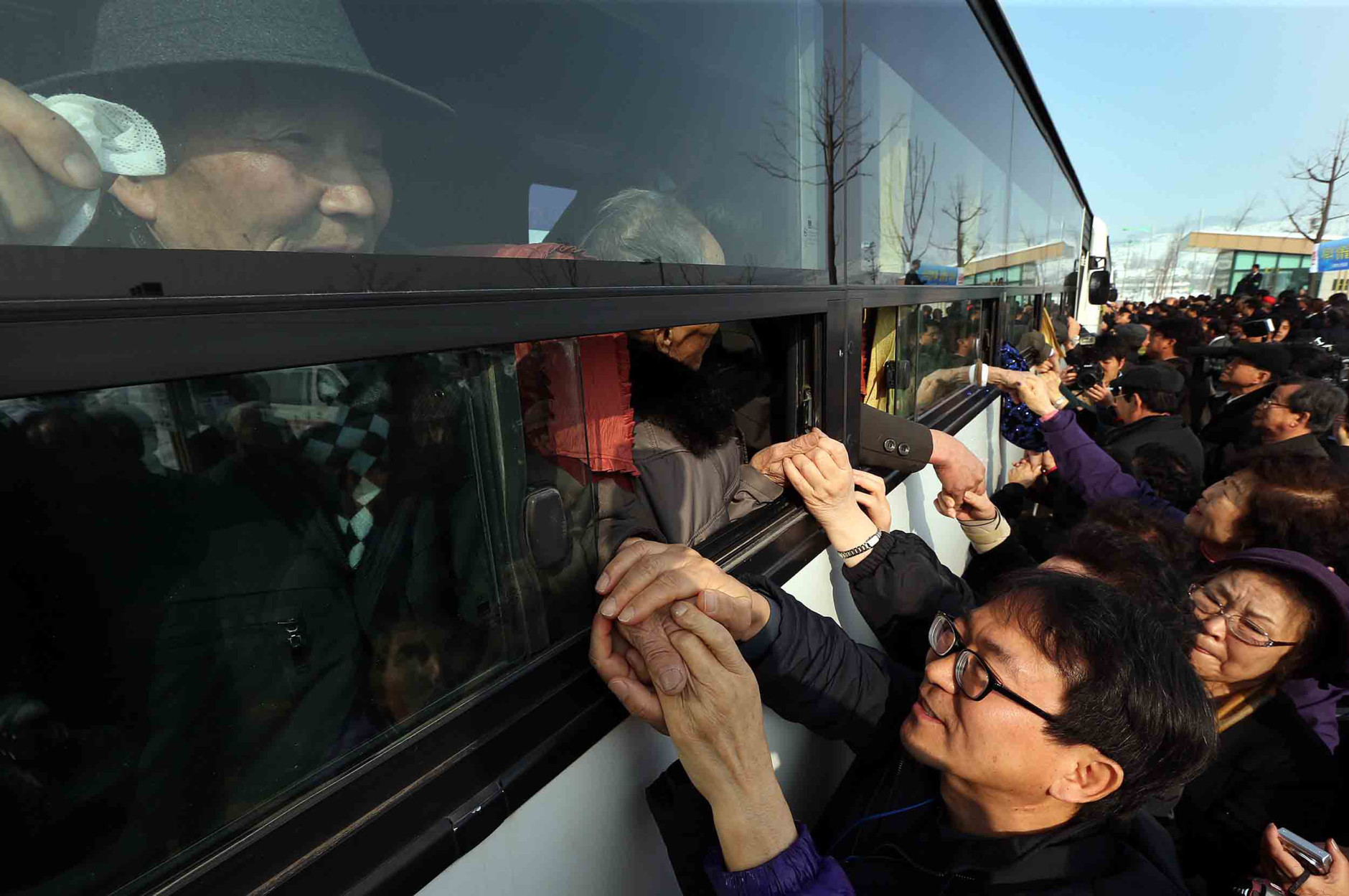 FOR USE AS DESIRED, YEAR END PHOTOS - FILE - South Koreans hold their North Korean relative's hands on a bus after the Separated Family Reunion Meeting at Diamond Mountain in North Korea, Tuesday, Feb. 25, 2014. The first reunions of North and South Koreans in more than three years have were held in North Korea. The final group of Koreans to participate in reunions ends Tuesday. (AP Photo/Yonhap, Lee Ji-eun, File) KOREA OUT