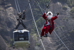 A man dressed as Santa Claus zip lines away from Sugar Loaf mountain after riding on top of a cable car in Rio de Janeiro, Brazil, Thursday, Dec. 18, 2014. The cable car company surprised tourists with a visit from Santa to celebrate Christmas. (AP Photo/Felipe Dana)