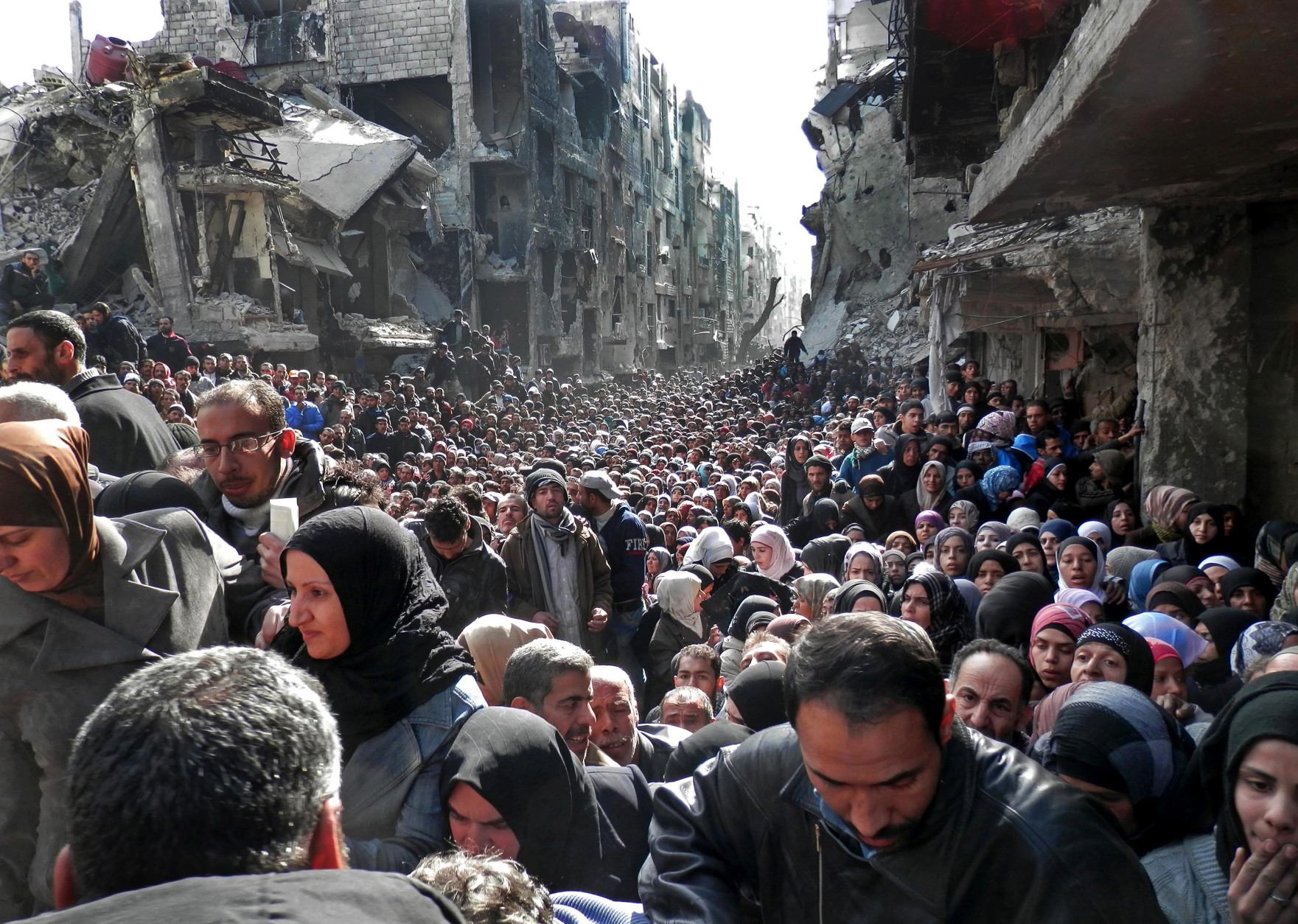 FOR USE AS DESIRED, YEAR END PHOTOS - FILE - This picture taken on Jan. 31, 2014, and released by the UNRWA, shows residents of the besieged Palestinian camp of Yarmouk, queuing to receive food supplies, in Damascus, Syria. A United Nations official called on warring sides in Syria to allow aid workers to resume distribution of food and medicine in a besieged Palestinian district of Damascus. The call comes as U.N. Secretary General Ban Ki-Moon urged Syrian government to authorize more humanitarian staff to work inside the country, devastated by its 3-year-old conflict. (AP Photo/UNRWA, File)