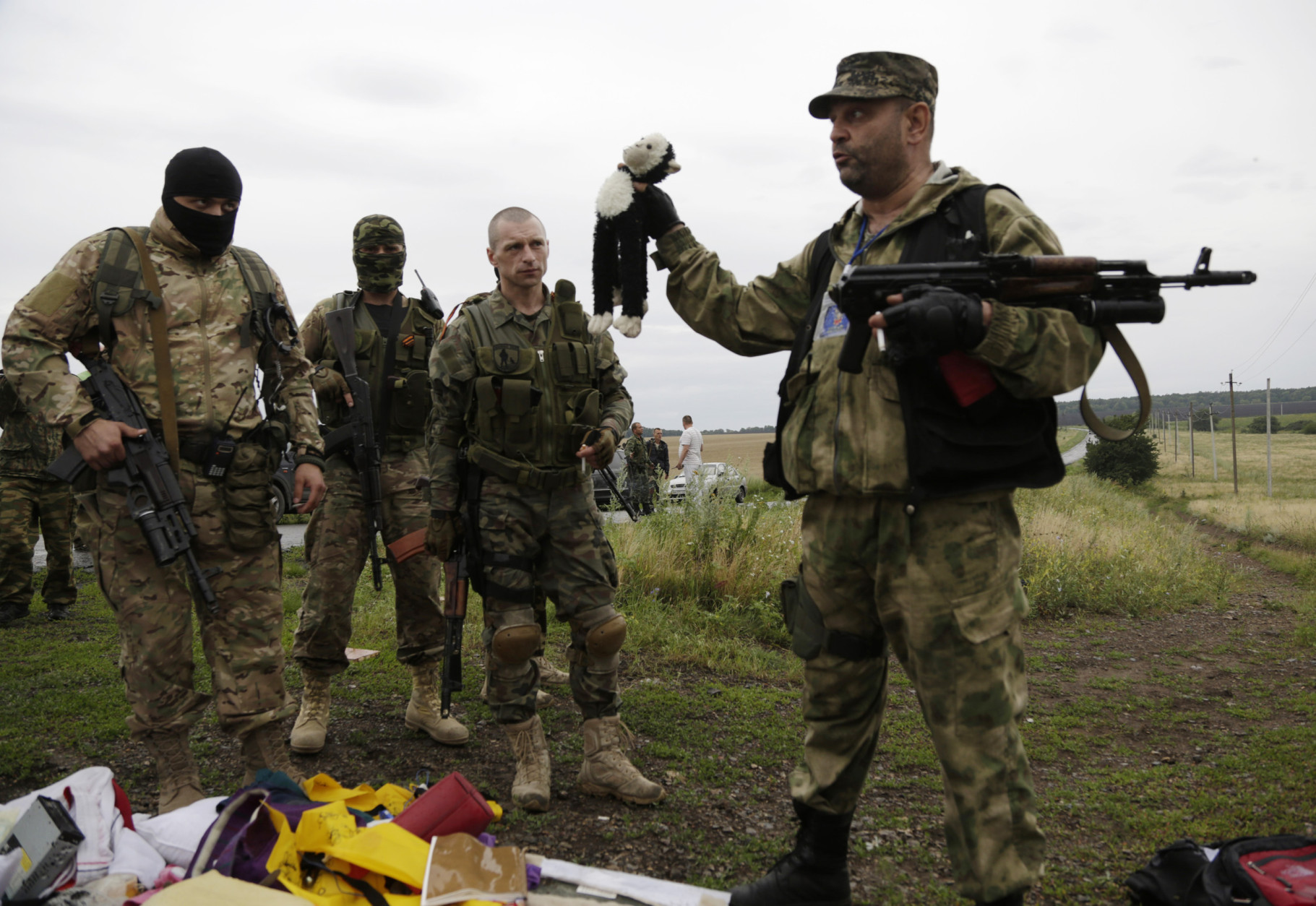 FOR USE AS DESIRED, YEAR END PHOTOS - FILE - A pro-Russian fighter holds up a toy found among the debris at the crash site of a Malaysia Airlines jet near the village of Hrabove, Friday, July 18, 2014. Emergency workers, police officers and even off-duty coal miners spread out across the sunflower fields and villages of eastern Ukraine, searching the wreckage of a Malaysia Airlines jet shot down as it flew high above the country's battlefield. The attack killed 298 people from nearly a dozen nations. (AP Photo/Dmitry Lovetsky, File)