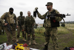 FOR USE AS DESIRED, YEAR END PHOTOS - FILE - A pro-Russian fighter holds up a toy found among the debris at the crash site of a Malaysia Airlines jet near the village of Hrabove, Friday, July 18, 2014. Emergency workers, police officers and even off-duty coal miners spread out across the sunflower fields and villages of eastern Ukraine, searching the wreckage of a Malaysia Airlines jet shot down as it flew high above the country's battlefield. The attack killed 298 people from nearly a dozen nations. (AP Photo/Dmitry Lovetsky, File)