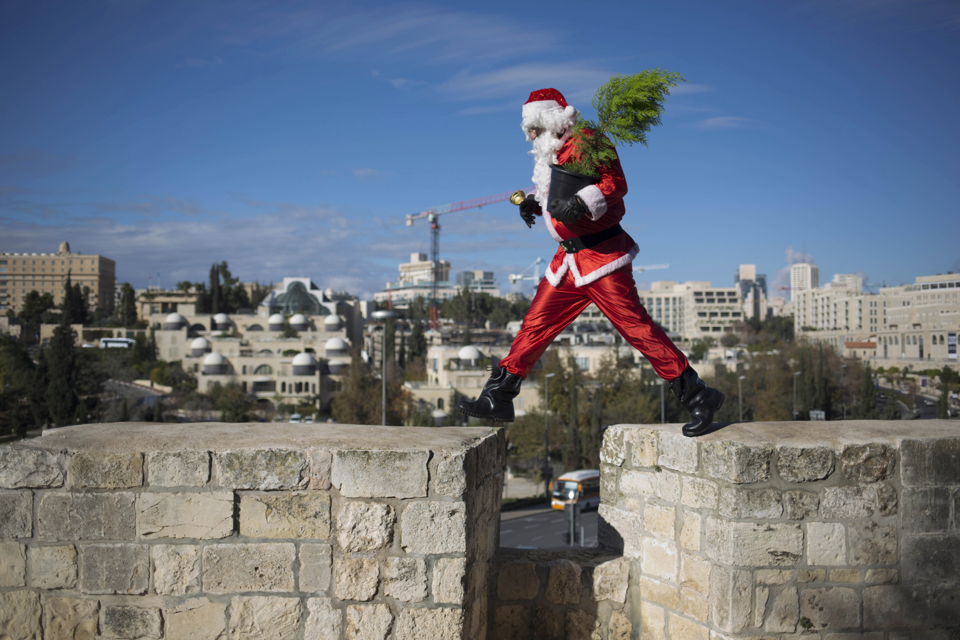 A man dressed as Santa Claus walks on the wall of the Old City in Jerusalem Monday, Dec. 22, 2014. (AP Photo/Dusan Vranic)