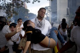 FOR USE AS DESIRED, YEAR END PHOTOS - FILE - A man carries a woman affected by tear gas launched by riot police at anti-government protesters in Caracas, Venezuela, Saturday, Feb. 22, 2014.  (AP Photo/Rodrigo Abd, File)