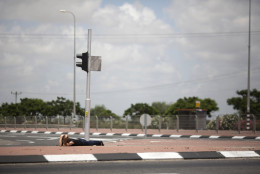FOR USE AS DESIRED, YEAR END PHOTOS - FILE - An Israeli woman takes cover as siren alarming sounds warning of rocket attacks by Palestinians militants from Gaza Strip in Ashkelon, southern Israel, Monday, July 14, 2014. (AP Photo/Ariel Schalit, File)