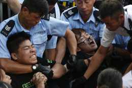 FOR USE AS DESIRED, YEAR END PHOTOS - FILE - Protesters are taken away by police officers after hundreds of protesters staged a peaceful sit-ins overnight on a street in the financial district in Hong Kong Wednesday, July 2, 2014, following a huge rally to show their support for democratic reform and oppose Beijing's desire to have the final say on candidates for the chief executive's job. (AP Photo/Kin Cheung, File)