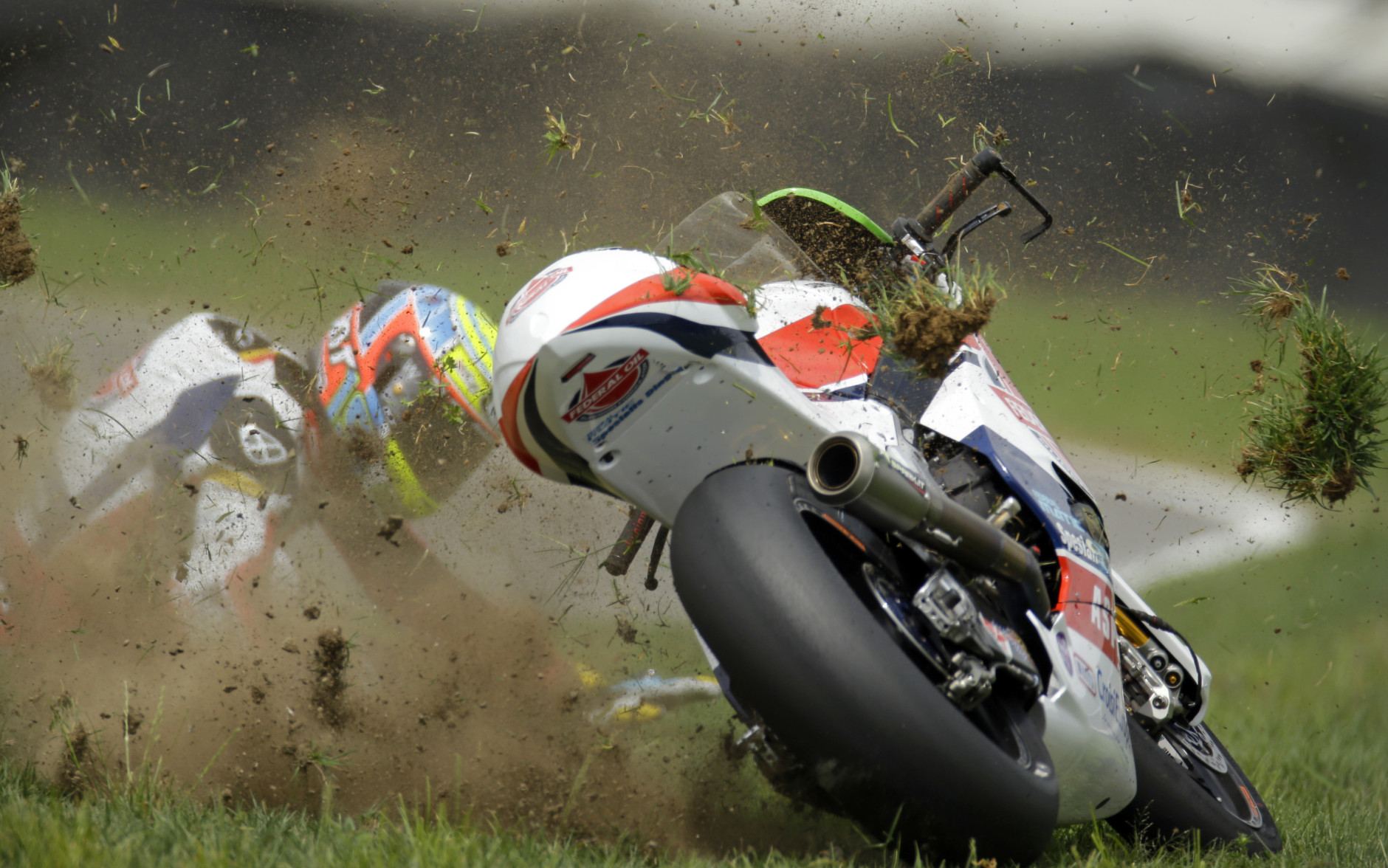 FOR USE AS DESIRED, YEAR END PHOTOS - FILE - Xavier Simeon, of Belgium, crashes during Indianapolis Moto 2 motorcycle race at the Indianapolis Motor Speedway in Indianapolis, Sunday, Aug. 10, 2014. (AP Photo/Michael Conroy, File)