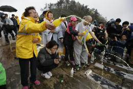 FOR USE AS DESIRED, YEAR END PHOTOS - FILE - A Buddhist monk and relatives of passengers aboard a sunken ferry spray alcohols during a Buddhist ceremony to pray for speedy rescue and their safety at a port in Jindo, south of Seoul, South Korea, Friday, April 18, 2014. The ferry flipped onto its side and filled with water off the southern coast of South Korea. (AP Photo/Lee Jin-man, File)