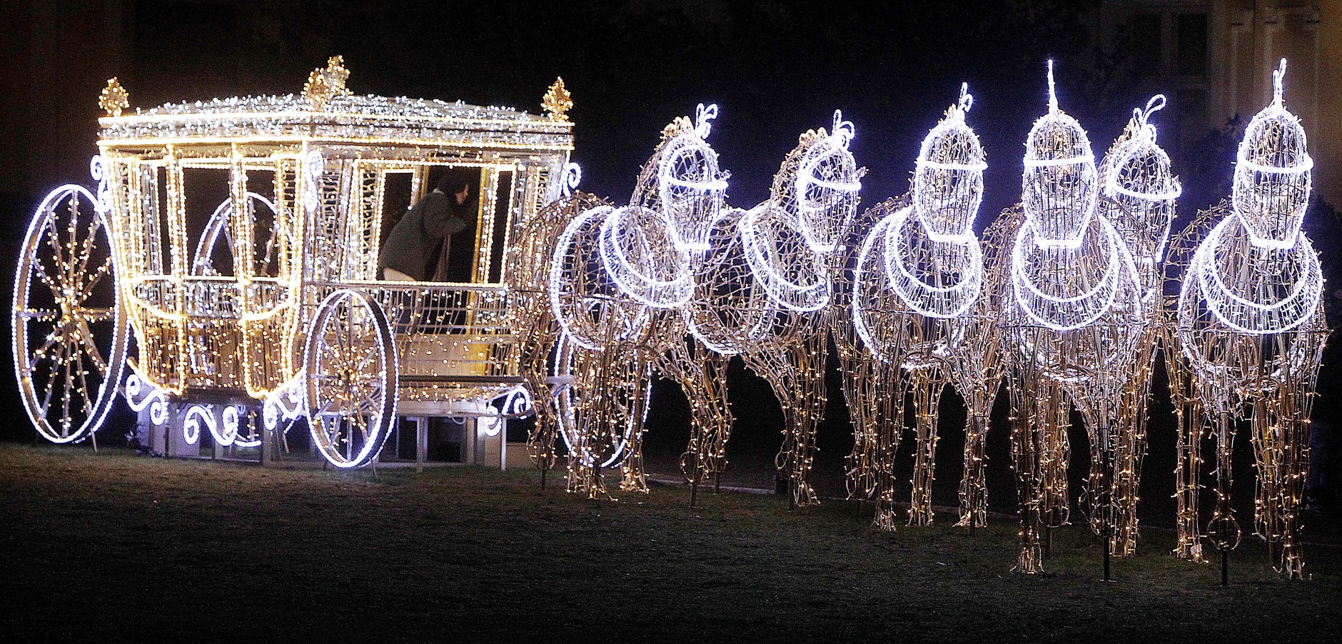 People walk near illuminated Christmas decorations at the Wilanow Palace in Warsaw, Poland, Thursday, Dec. 18, 2014.(AP Photo/Czarek Sokolowski)