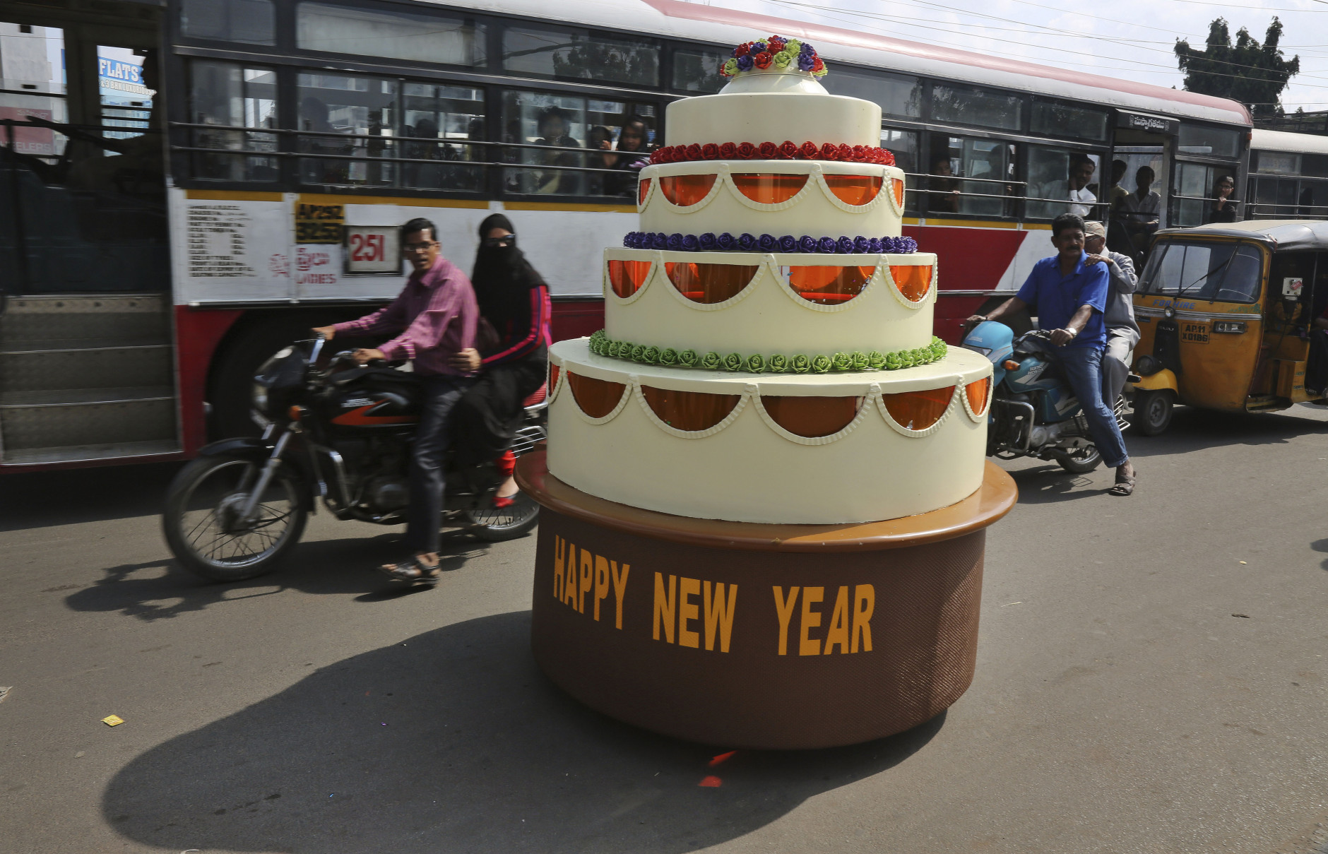 Sudhakar Yadav, the designer of a cake-shaped car, rides it on a street on New Years eve in Hyderabad, India, Wednesday, Dec. 31, 2014. The single seater vehicle is powered by a 100 cc engine from a road sweeping machine and can travel unto 10 kilometers per hour (6 miles per hour). (AP Photo/Mahesh Kumar A.)