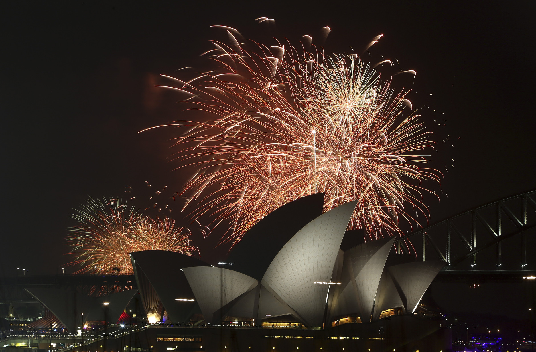Fireworks explode over the Opera House and the Harbour Bridge during New Years Eve celebrations in Sydney, Australia, Wednesday, Dec. 31, 2014. Thousands of people crammed into Lady Macquaries Chair to watch the annual fireworks show. (AP Photo/Rob Griffith)