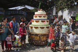 Indians stand near a cake-shaped car designed by Sudhakar Yadav on New Years eve in Hyderabad, India, Wednesday, Dec. 31, 2014. The triple decker car is powered with a 100cc engine of a road sweeping machine. The single seater car travels unto 10 kilometers per hour (6 miles per hour). (AP Photo/Mahesh Kumar A.)
