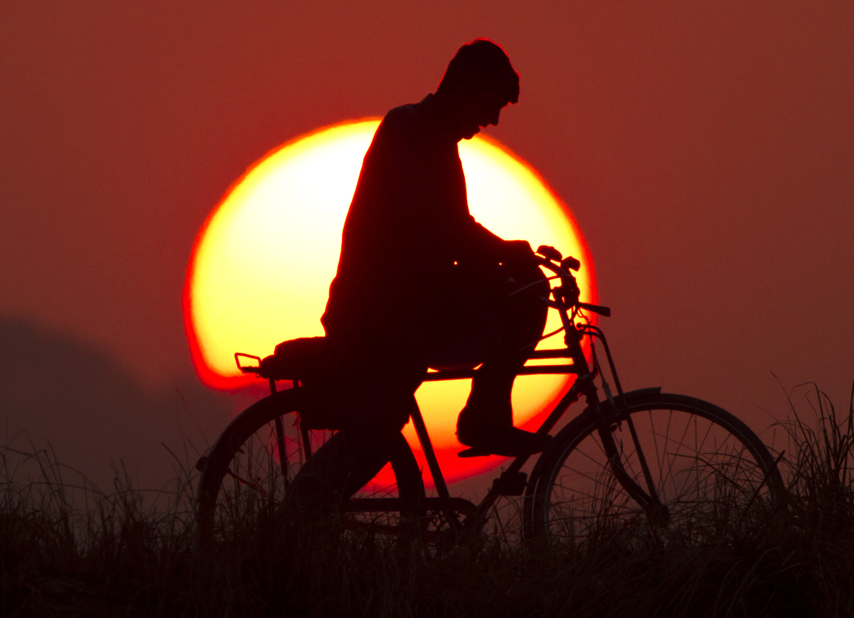 A Pakistani cyclist rides during the last sunset of the year on the outskirts of Islamabad, Pakistan, Wednesday, Dec. 31, 2014. (AP Photo/Anjum Naveed)