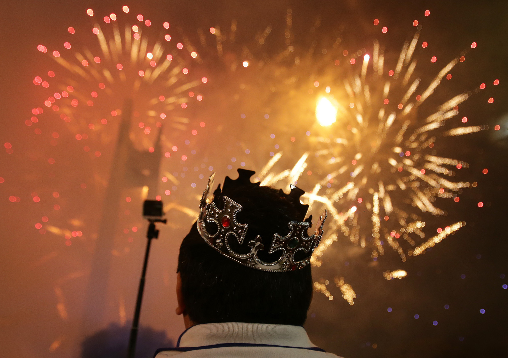 A Filipino watches a fireworks display at the Quezon Memorial Circle in suburban Quezon city, north of Manila, Philippines on Thursday, Jan. 1, 2015. (AP Photo/Aaron Favila)