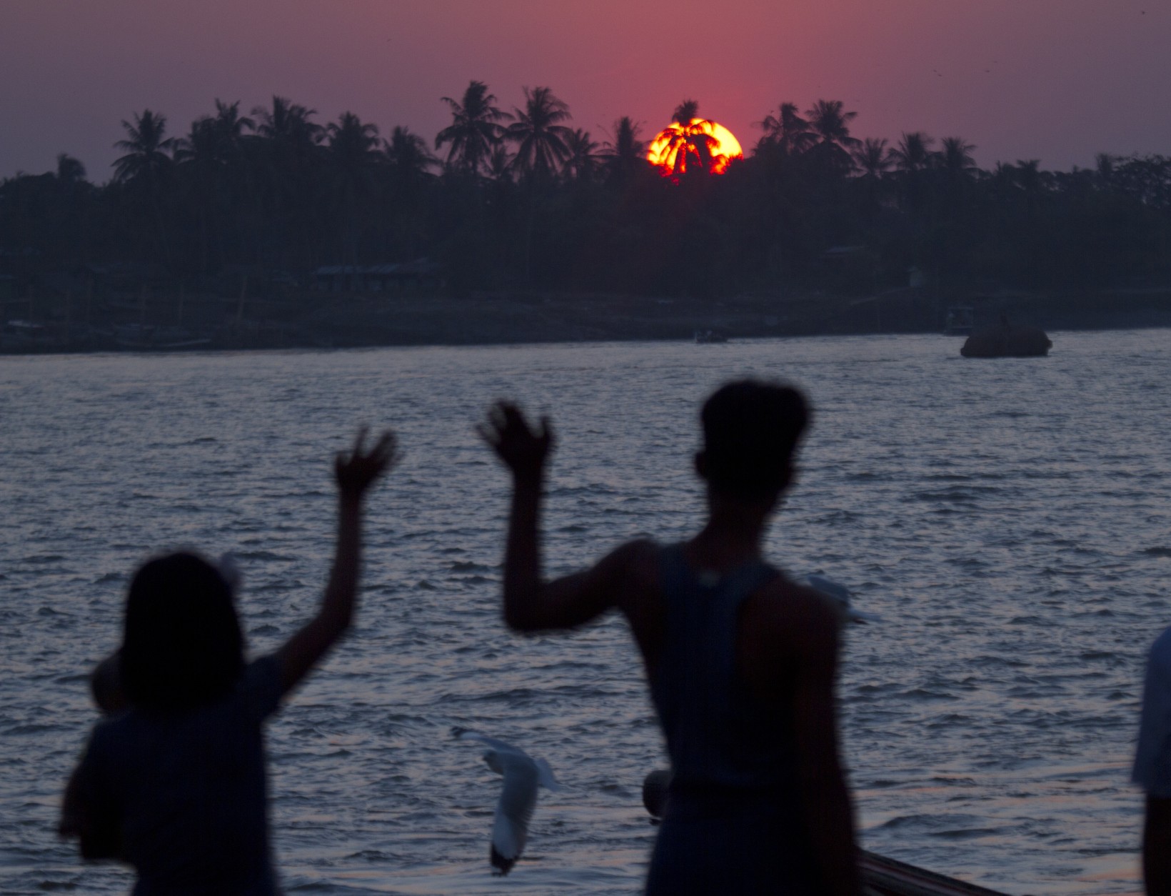 A couple waves during the last sunset of the year at a jetty at Yangon river in Yangon, Myanmar Wednesday, Dec. 31, 2014. (AP Photo/Khin Maung Win)