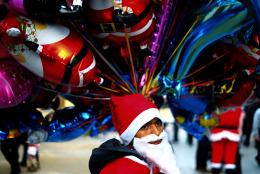 A migrant in the Santa Claus costume sells balloons at Ledra, a main shopping street of capital Nicosia, Cyprus, Saturday, Dec. 20,  2014, during the Christmas celebrations. (AP Photo/Petros Karadjias)