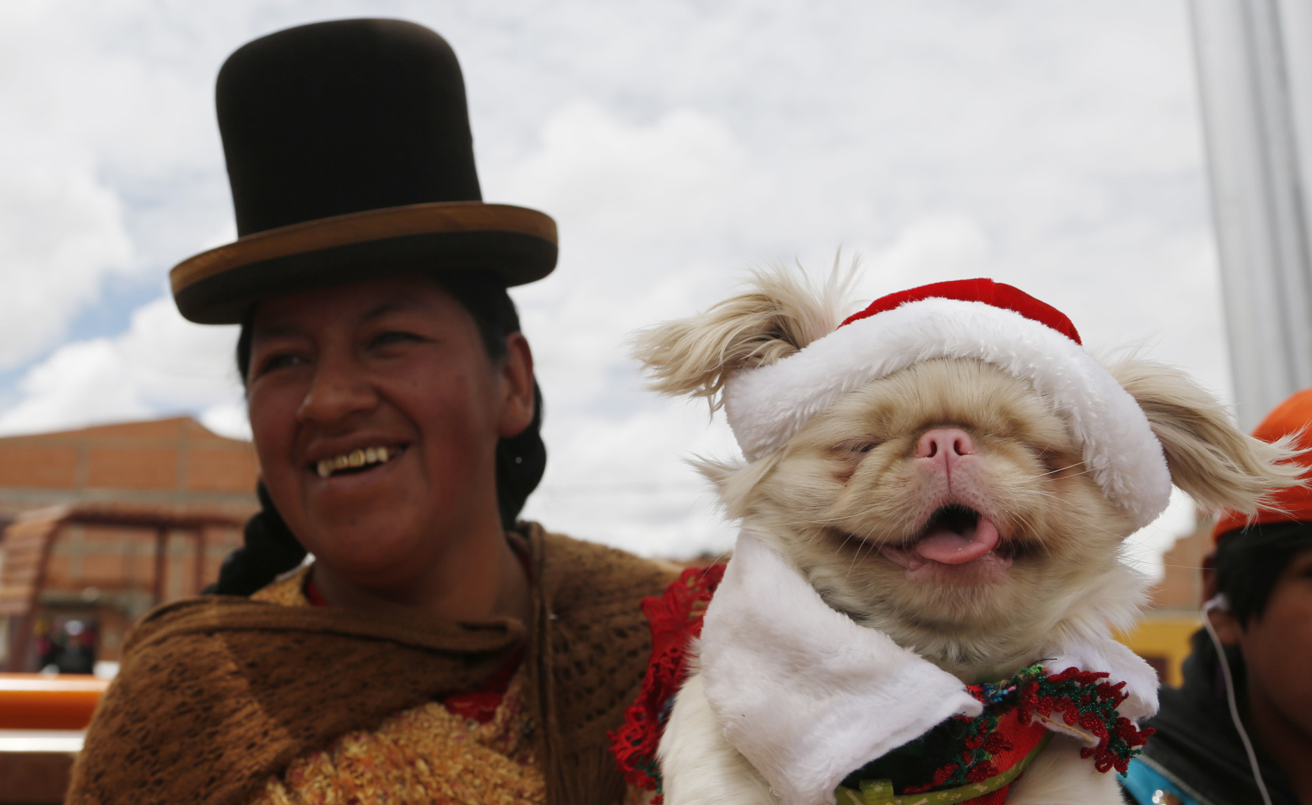 An Aymara indigenous woman carries her pet to a Christmas costume contest for dogs in El Alto, Bolivia, Saturday, Dec. 20, 2014. About 50 dogs participated in the event organized by zoonosis. (AP Photo/Juan Karita)