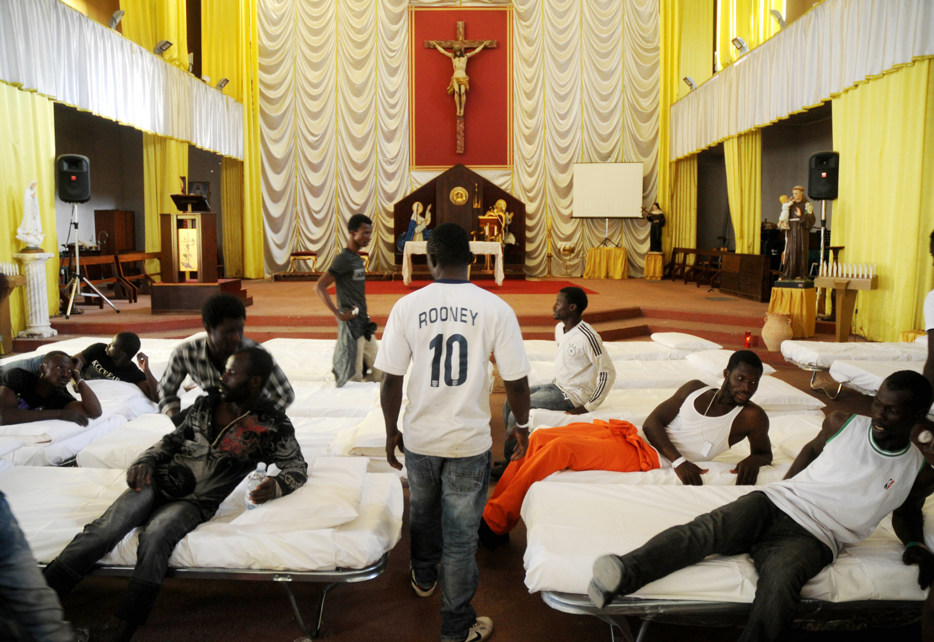 FOR USE AS DESIRED, YEAR END PHOTOS - FILE - In this picture taken Sunday, June 15, 2014, migrants from Africa are temporarily sheltered in the Catholic church of  St. Curato D'Ars in Palermo, Sicily, Italy. The Italian coast guard and navy have rescued more than 300 migrants whose boats ran into trouble in the Mediterranean Sea and recovered the bodies of 10 migrants whose dinghy had overturned.  (AP Photo/Alessandro Fucarini, File)