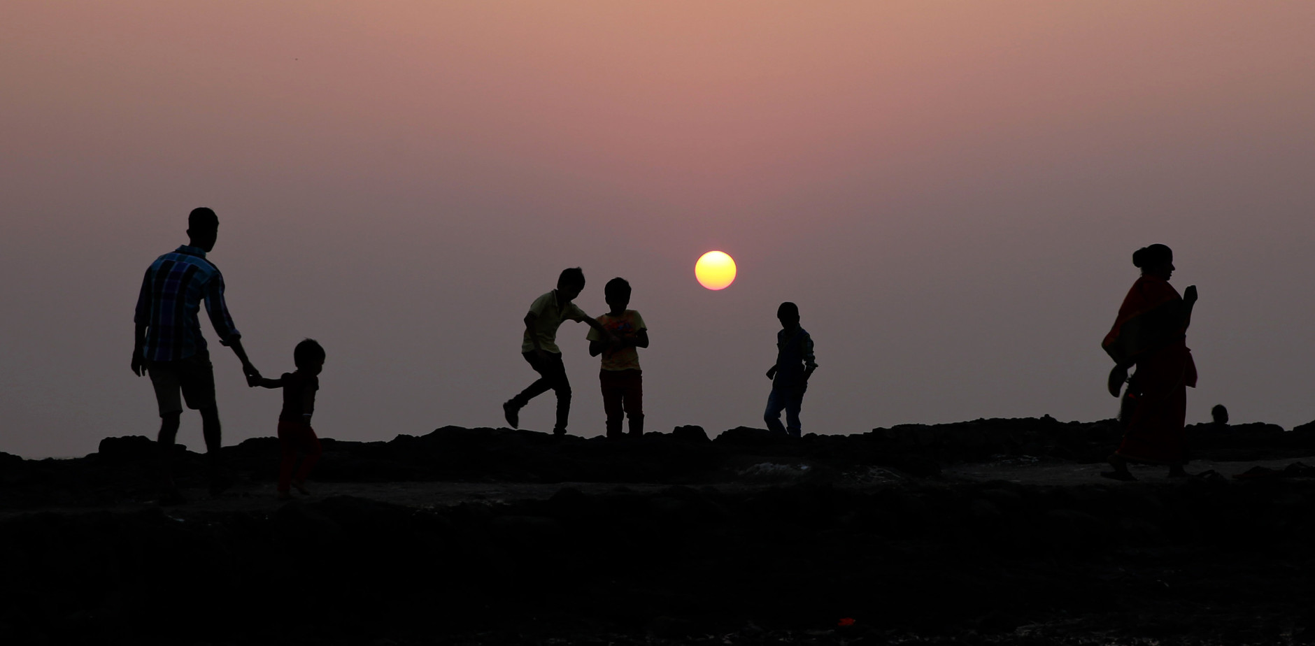 Children play on the shores of the Arabian sea as the last sunset of 2014 is seen in the background in Mumbai, India, Wednesday, Dec 31, 2014. (AP Photo/Rafiq Maqbool)