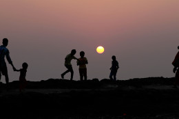 Children play on the shores of the Arabian sea as the last sunset of 2014 is seen in the background in Mumbai, India, Wednesday, Dec 31, 2014. (AP Photo/Rafiq Maqbool)