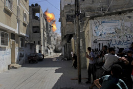 FOR USE AS DESIRED, YEAR END PHOTOS - FILE - Palestinians take cover as an Israeli strike on a building causes a ball of fire and smoke to rise in the Rafah refugee camp, southern Gaza Strip, Saturday, Aug. 23, 2014. (AP Photo/Hatem Ali, File)