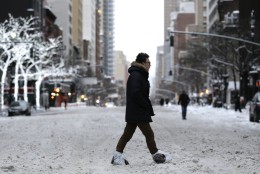 A man wearing plastic bags on his feet crosses a snowy avenue in New York, Tuesday, Jan. 27, 2015. A storm packing blizzard conditions spun up the East Coast early Tuesday, pounding parts of coastal New Jersey northward through Maine with high winds and heavy snow. (AP Photo/Seth Wenig)