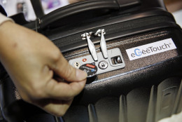 A man demonstrates the eGeeTouch Smart Luggage Lock by Digi-Pas at CES Unveiled, a media preview event for CES International, Sunday, Jan. 4, 2015, in Las Vegas. The device allows you to unlock luggage with a smart tag or mobile device. (AP Photo/John Locher)