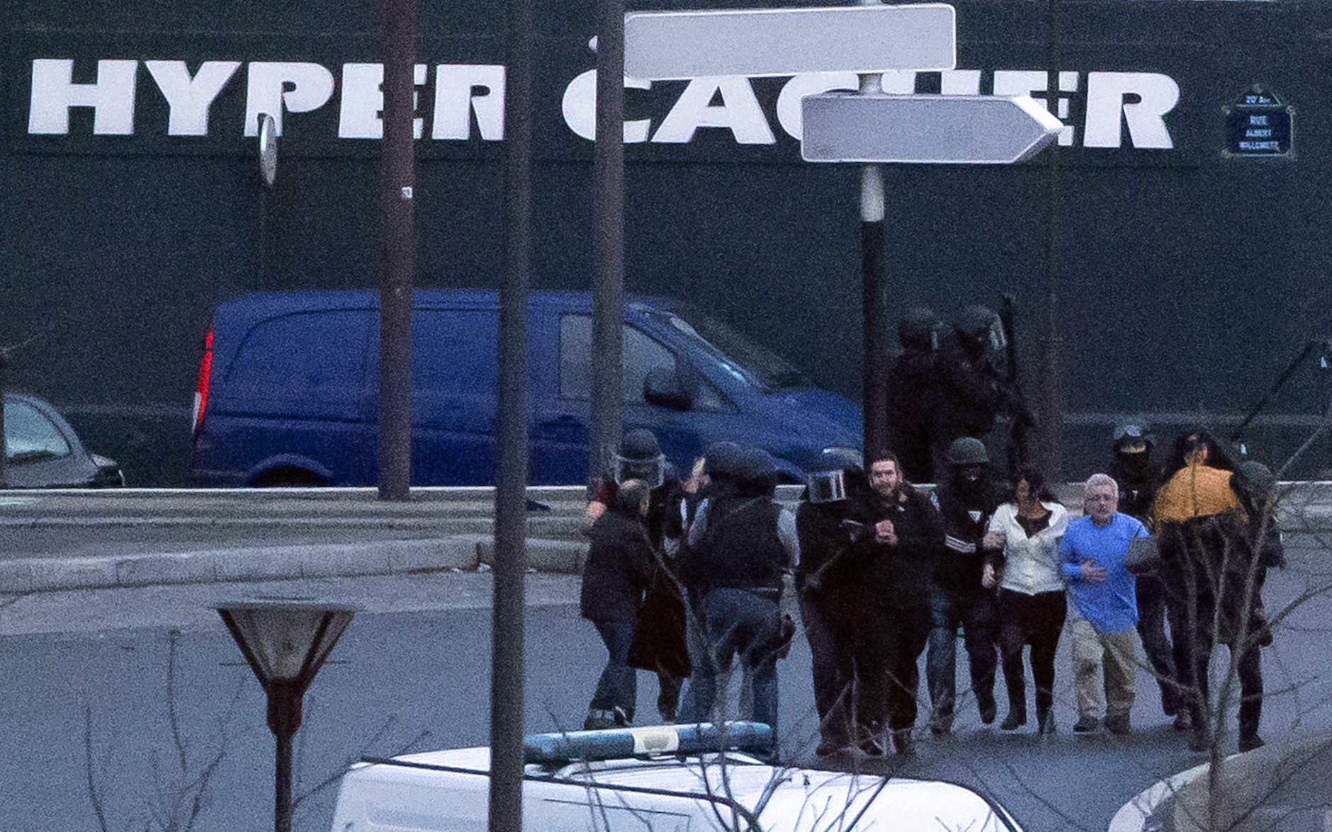 Security officers escort released hostages after they stormed a kosher market to end a hostage situation, Paris, Friday, Jan. 9, 2015. Explosions and gunshots were heard as police forces stormed a kosher grocery in Paris where a gunman was holding at least five people hostage. (AP Photo/Michel Euler)