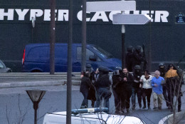 Security officers escort released hostages after they stormed a kosher market to end a hostage situation, Paris, Friday, Jan. 9, 2015. Explosions and gunshots were heard as police forces stormed a kosher grocery in Paris where a gunman was holding at least five people hostage. (AP Photo/Michel Euler)