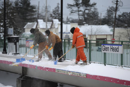 Long Island Railroad workers clear the platform of snow at the Glen Head station  on Tuesday, Jan. 27, 2015, in Glen Head, N.Y. Travel on the railroad was suspended due to a blizzard that hit the New York area overnight into this morning. (AP Photo/Kathy Kmonicek)