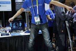 Takuma Iwasa demonstrates the Cerevo XON Snow-1 snowboard bindings at CES Unveiled, a media preview event for CES International, Sunday, Jan. 4, 2015, in Las Vegas. The bindings have pressure sensors to analyze your snowboarding technique. (AP Photo/John Locher)