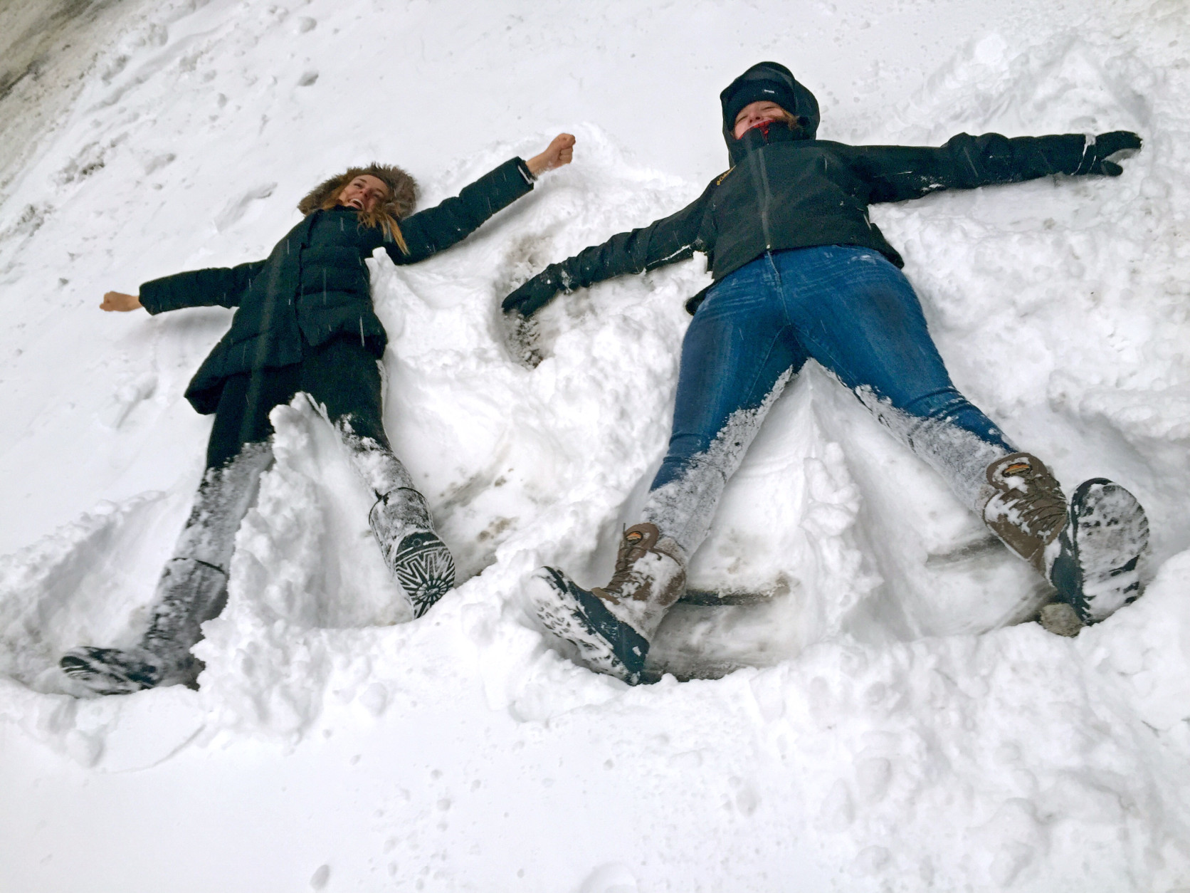 Bianca Hillier, left, of Columbus, Ohio, and Eloise Pollard of London take advantage of a snowtorm travel ban to do something they never envisioned: making snow angels on a normally busy stretch of Manhattans Tenth Avenue at West 34th Street in New York, Tuesday Jan. 27, 2015. A howling blizzard heaped snow on Boston, the rest of eastern Massachusetts and parts of Long Island on Tuesday, delivering wind gusts topping 75 mph, but it failed to live up to the hype farther south in Philadelphia and New York City, which canceled its travel ban in the morning amid better-than-expected weather conditions. (AP Photo/Jennifer Peltz)