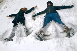 Bianca Hillier, left, of Columbus, Ohio, and Eloise Pollard of London take advantage of a snowtorm travel ban to do something they never envisioned: making snow angels on a normally busy stretch of Manhattans Tenth Avenue at West 34th Street in New York, Tuesday Jan. 27, 2015. A howling blizzard heaped snow on Boston, the rest of eastern Massachusetts and parts of Long Island on Tuesday, delivering wind gusts topping 75 mph, but it failed to live up to the hype farther south in Philadelphia and New York City, which canceled its travel ban in the morning amid better-than-expected weather conditions. (AP Photo/Jennifer Peltz)