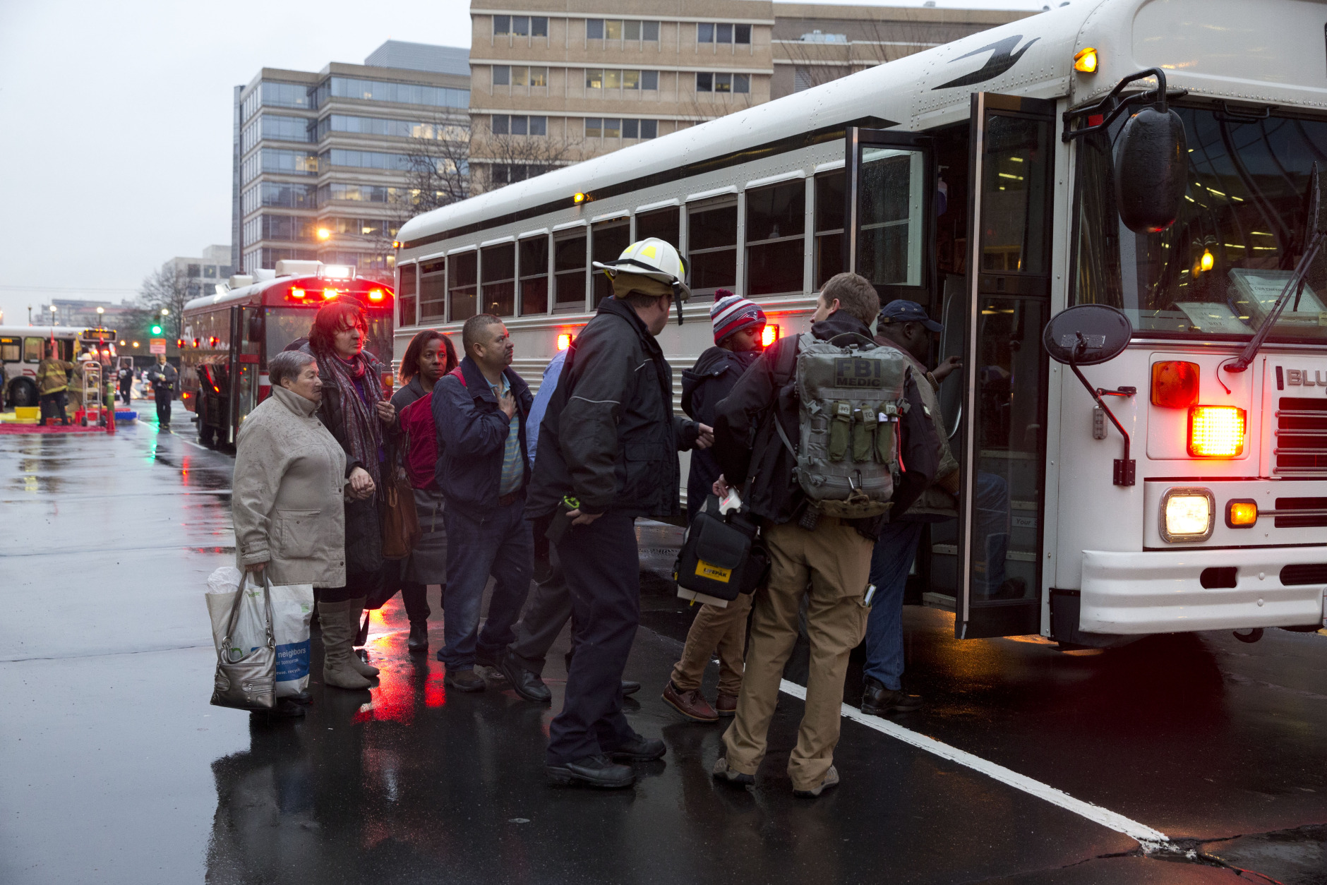 Coughing people are taken onto a bus as they are evacuated from a smoke filled Metro train Monday, Jan. 12, 2015.  (AP Photo/Jacquelyn Martin)